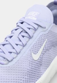 Lilla võrkmaterjalist spordijalanõu tekstuuriga pinnaga, lameede nööpidega ja valge swoosh-logo. Pehme kaeluse ja peene lavendlitoonis aktsentidega.