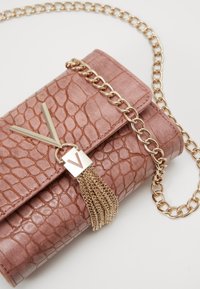 Růžová koženka clutch s krokodýlím vzorem, zlatým řetězovým popruhem, detailem s třásněmi a geometrickým kovovým akcentem. Kompaktní obdelníkový design.