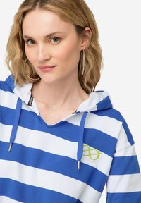 Felpa con cappuccio a strisce blu e bianche con un logo verde. Caratterizzata da un cappuccio con cordino e accenti in metallo argentato. Tessuto morbido e leggero.