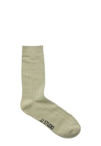 Lichtgroene geribde sok met een gladde textuur, voorzien van een versterkte teen en hiel. "JJ STUDIO" logo gedrukt op de zool.