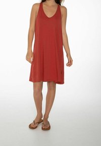 Robe rouge sans manches avec un décolleté en V, fabriquée en tissu doux, coupe trapèze et une coupe décontractée, avec une petite étiquette logo près de l'ourlet.