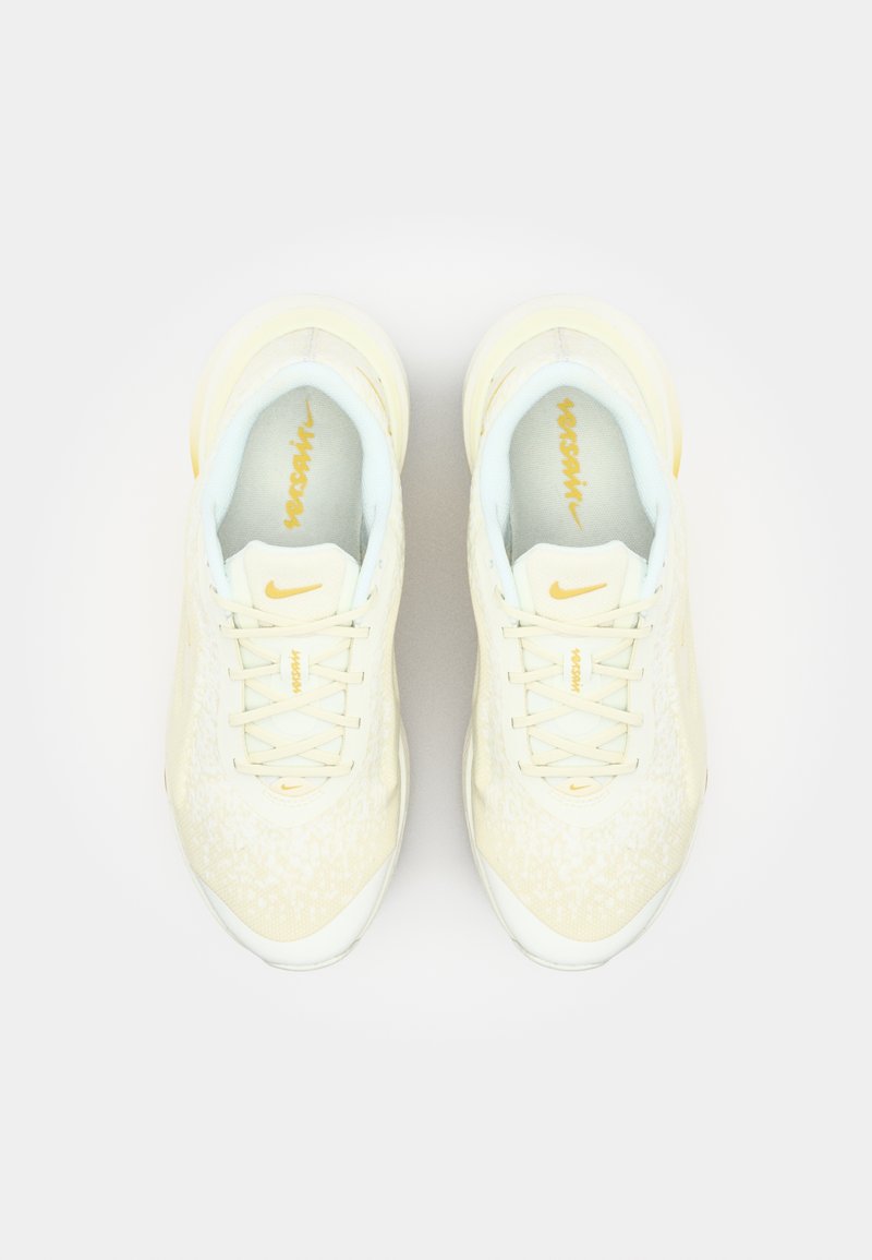 Beżowe buty sportowe z teksturowaną powierzchnią, jasnoniebieskimi akcentami i żółtymi detalami; posiadają tradycyjną podeszwę i wzór sznurowania.