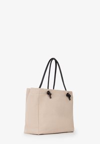 Borsa a tracolla in tessuto beige con manici intrecciati neri, caratterizzata da accenti annodati e una forma strutturata. Design semplice, texture liscia.