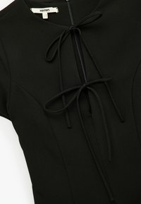 Schwarzes Kleid mit rundem Halsausschnitt, kurzen Ärmeln und einem Frontreißverschluss mit einer gebundenen Detail. Aus glattem Stoff mit einer taillierten Silhouette gefertigt.