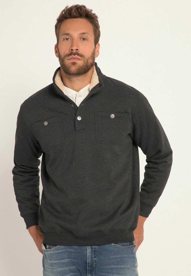 Pullover grigio scuro con colletto alto, due tasche sul petto, chiusura frontale con bottoni e un interno morbido foderato. Realizzato in tessuto texturizzato.