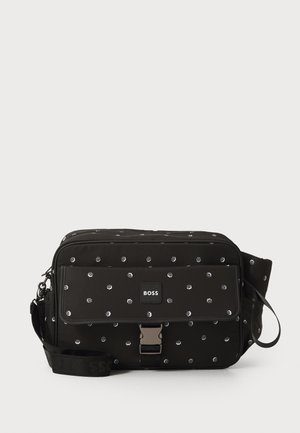 Črna torba za sporočila iz najlona z belim pikčastim vzorcem, ima sprednji pokrov, srebrno strojno opremo in naramnico z logotipom.