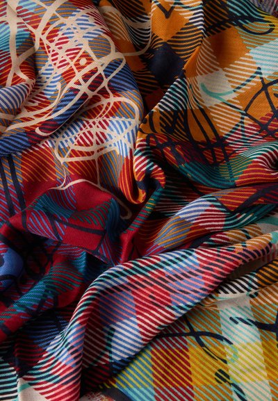Χρωματιστό ύφασμα με αφηρημένα γεωμετρικά σχέδια, που περιλαμβάνουν ρίγες, καμπύλες και σπείρες σε αποχρώσεις του κόκκινου, μπλε, κίτρινου, πορτοκαλί και πράσινου.