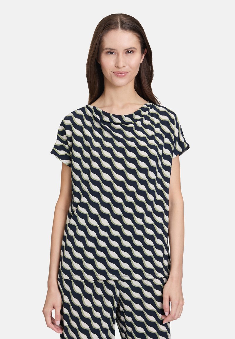 Koszulka z krótkim rękawem w kolorze granatowym z falistym wzorem w odcieniu kremowym. Posiada luźną, drapowaną linię dekoltu oraz komfortowy krój, wykonana jest z gładkiego materiału.