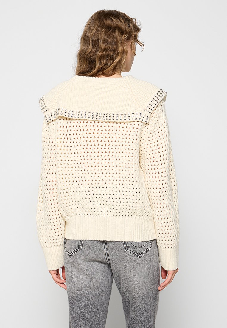 Cremfarbener gestrickter Pullover mit einem strukturierten offenen Design, einem gerippten Saum und einem markanten Kragen mit Metalldomischen entlang der Kante.