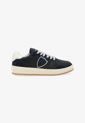 Baskets navy et noires en cuir et daim avec un bout rond, lacets blancs et semelle en caoutchouc beige. Avec un logo en forme de bouclier sur le côté.