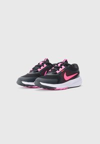 Une paire de chaussures de course Nike noires et roses avec des semelles intermédiaires blanches et des accents roses, présentée de côté sur un fond blanc.