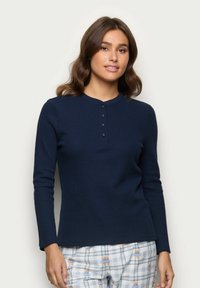 Granatowy, prążkowany top z długim rękawem, z okrągłym dekoltem i plaketą na cztery guziki; połączony z jasnymi, w kratkę spodniami od piżamy ozdobionymi kwiatowym wzorem.