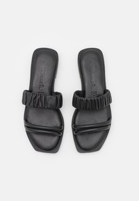 Zwarte slide-sandalen met een gevoerde elastische band, een glad leren voetbed en twee accentlijnen over de onderkant. Maat 37 genoteerd.
