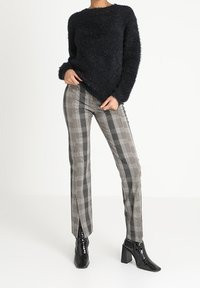 Black fluffy knit sweater, gray plaid trousers with front slits, and black patent ankle boots with a block heel.