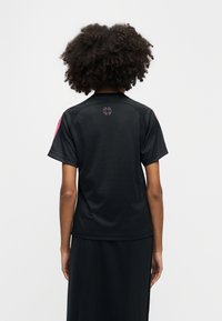 Μαύρο αθλητικό μπλουζάκι με κοντά μανίκια, λείο ύφασμα, στρογγυλή λαιμόκοψη, ροζ λεπτομέρειες στους ώμους, ροζ λογότυπο στο πίσω μέρος.