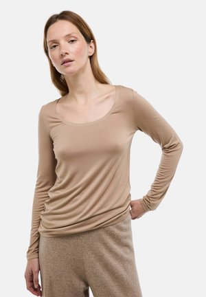 Haut à manches longues avec encolure dégagée, beige, en tissu doux et ajusté, à la texture lisse et léger drapé à la taille.