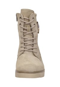 Beige suede veterschoenen tot de enkel met zijrits en lichtbruine rubberen zool, van voren bekeken.
