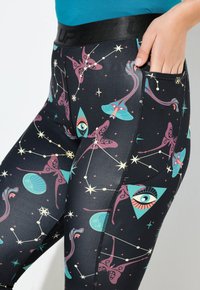Leggings met een zwarte basis en kleurrijke hemelse patronen, waaronder sterren, ogen en vormen. Elastaan band en zijzak detail.