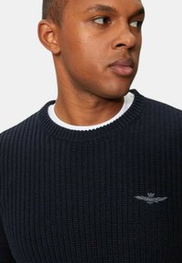 Pullover di colore navy in maglia con texture a costine, design a girocollo, caratterizzato da un piccolo logo ricamato sul petto.
