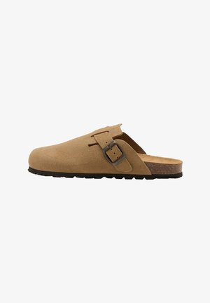 Sabot en daim marron clair à enfiler avec boucle latérale réglable et semelle en caoutchouc noir, montré de profil sur fond blanc.
