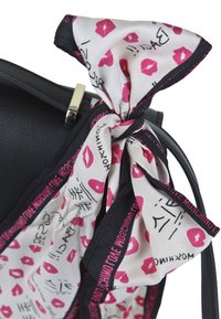 Borsa nera con una finitura lucida, caratterizzata da una sciarpa a motivo rosa e bianco con motivi labbra e testi. Dettagli in metallo argentato visibili.