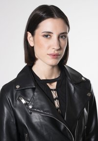 Zwarte leren motorjack met zilverkleurige hardware, ritszakken en een notch kraag. Gestructureerde afwerking en gedetailleerde stiksels aan de voorkant.