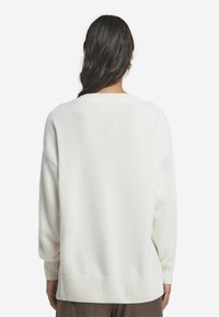 Wei�ßer gestrickter Pullover mit gerippten Bündchen und Saum. Lässige Passform mit herunterhängenden Schultern, weicher Textur und minimalistischer Gestaltung. Rückansicht.