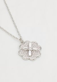 Srebrna cvetna ogrlica s skupino prozornih draguljev, ki vključuje osrednji okrogli kamen in polirano verigo.