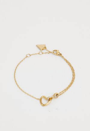 Gold chain bracelet featuring heart and infinity symbols, with a small triangular tag and a lobster clasp. Accented with clear rhinestones.