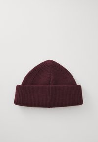 Burgunderstrikket lue med ribbete tekstur, med en brettet mansjett og en avsmalnende topp. Mykt materiale som er passende for kaldt vær.