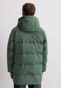 Zielona pikowana kurtka z kapturem, przeszyciami i nieco dłuższym tyłem, wykonana z gładkiego, lekkiego materiału.