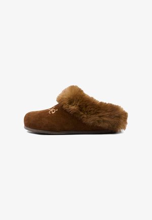 Zapatilla marrón de ante sin cordones con forro grueso y peludo alrededor del tobillo y texto bordado en el lateral, mostrada de perfil.