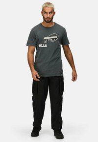 Šedé bavlněné tričko s bílým grafikou buvola a textem "BILLS." Vytvořeno s černými cargo kalhotami a černými teniskami.