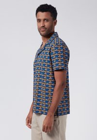Camisa de botones de manga corta con un patrón geométrico en azul, amarillo y marrón. Hecha de una tela ligera, con cuello y un corte relajado.