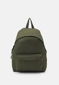 Mochila de tela verde con forma redondeada, bolsillo delantero con cremallera y asa superior. Superficie texturizada y correas reforzadas para mayor soporte.