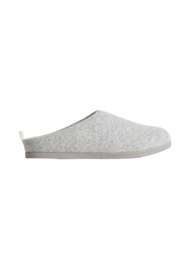 Chausson gris clair à enfiler avec dessus en feutre doux, semelle plate et petite languette de tirage au talon, présenté en profil latéral sur fond blanc.