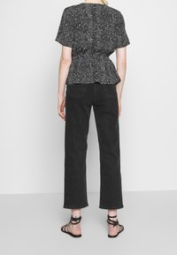 Černobílý vzorovaný peplum top s krátkými rukávy, kombinovaný s černými rovnými džíny s vysokým pasem a černými sandály na pásky.