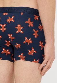 Boxers azuis escuros para homem com padrão repetido de homens de gengibre. Feitos de tecido macio, com cintura confortável gravada com "HAPPY".