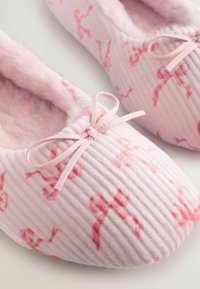 Roze geribbelde slippers met zachte, fluffy voering. Voorzien van een delicaat strikje en een subtiele dansafdruk. Rond gevormd voor extra comfort.