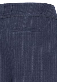 Gros plan sur un pantalon gris à fines rayures montrant la ceinture, les passants et le détail de la poche arrière.