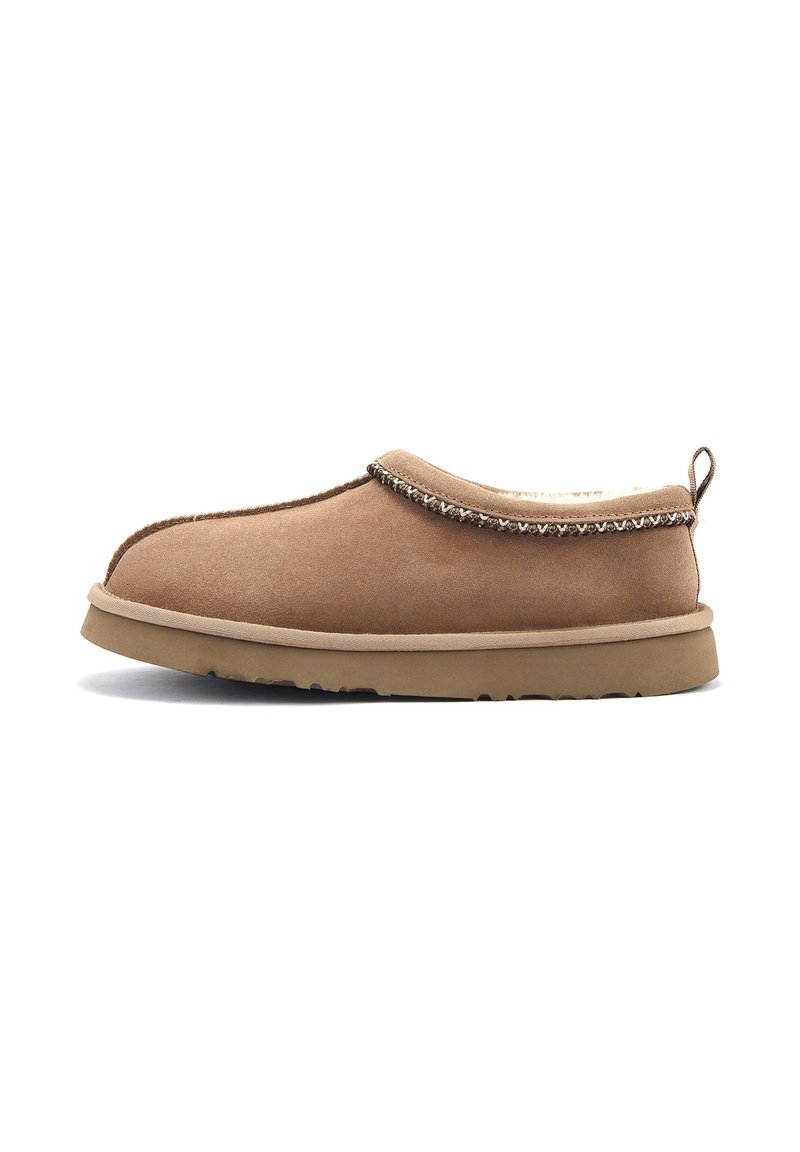 Scarpa slip-on in suede marrone con interno imbottito, cuciture decorative lungo il bordo e suola in gomma. Superficie testurizzata, design a profilo basso.