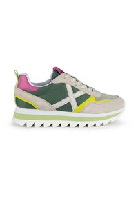 Zapatillas con una combinación de ante gris y tela verde, con una suela blanca gruesa, acentos en rosa y amarillo, y una lengüeta del talón verde.