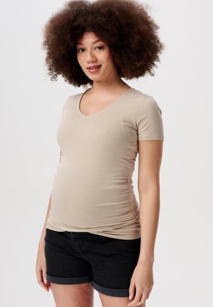Beige geripptes Umstandstop mit V-Ausschnitt und kurzen Ärmeln, kombiniert mit schwarzen Denim-Shorts mit umgeschlagenen Säumen. Glatte Textur über das gesamte Kleidungsstück.