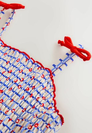 Smokots tops ar sarkanu un zilu svītru rakstu, ar sarkaniem akcentiem un saitēm, izgatavots no viegla auduma ar teksturētu apdari.