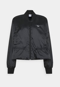 Svart kort jacka gjord av ett mjukt och lätt tyg. Har elastiska manschetter, en framdragkedja, sidofickor och en liten logotyp på bröstet.