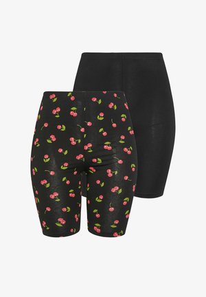 Dos pares de pantalones cortos negros para bicicleta, uno con estampado de cerezas rojas y hojas verdes, y el otro negro liso, mostrados sobre un fondo blanco.