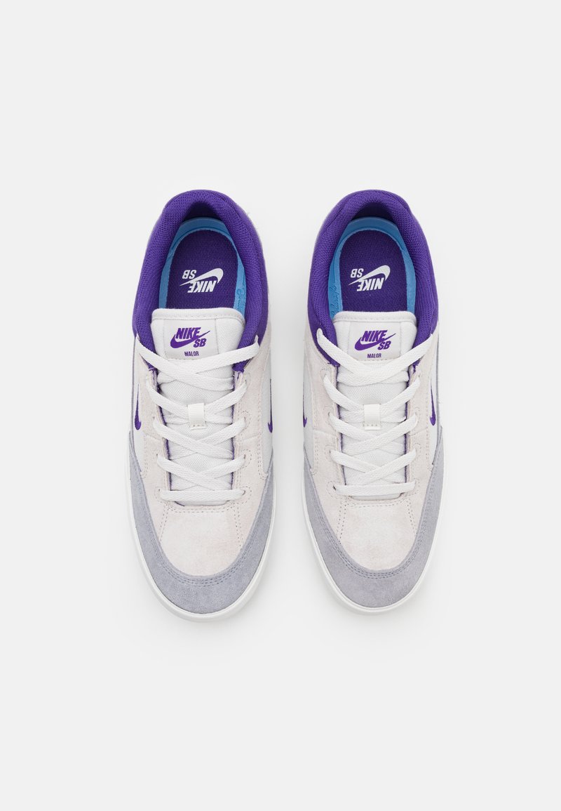 Nike SB Sneakers, die eine Mischung aus hellgrauem und weißem Wildleder, lilafarbenen Akzenten, weißen Schnürsenkeln und einer blauen Innensohle mit Branding aufweisen.