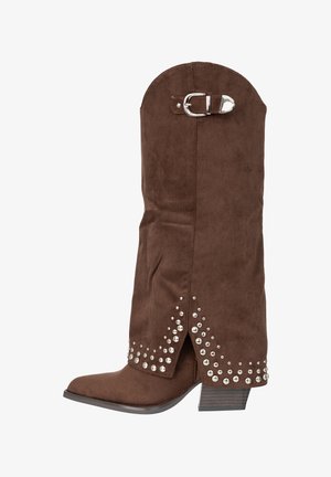 Stivale in camoscio marrone a metà polpaccio con borchie argentate lungo l'orlo e una fibbia decorativa argentata vicino alla parte superiore, caratterizzato da un tacco basso a blocco.