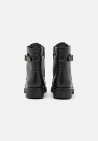 Czarne skórzane botki za kostkę o gładkiej powierzchni. Posiadają złote klamry oraz boczne zamki błyskawiczne. Grube gumowe podeszwy, okrągłe noski.