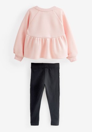 Svetloružová mikina s dlhými rukávmi, s nariaseným pásom a raglánovými rukávmi, v kombinácii s čiernymi legínami s elastickým pásom.